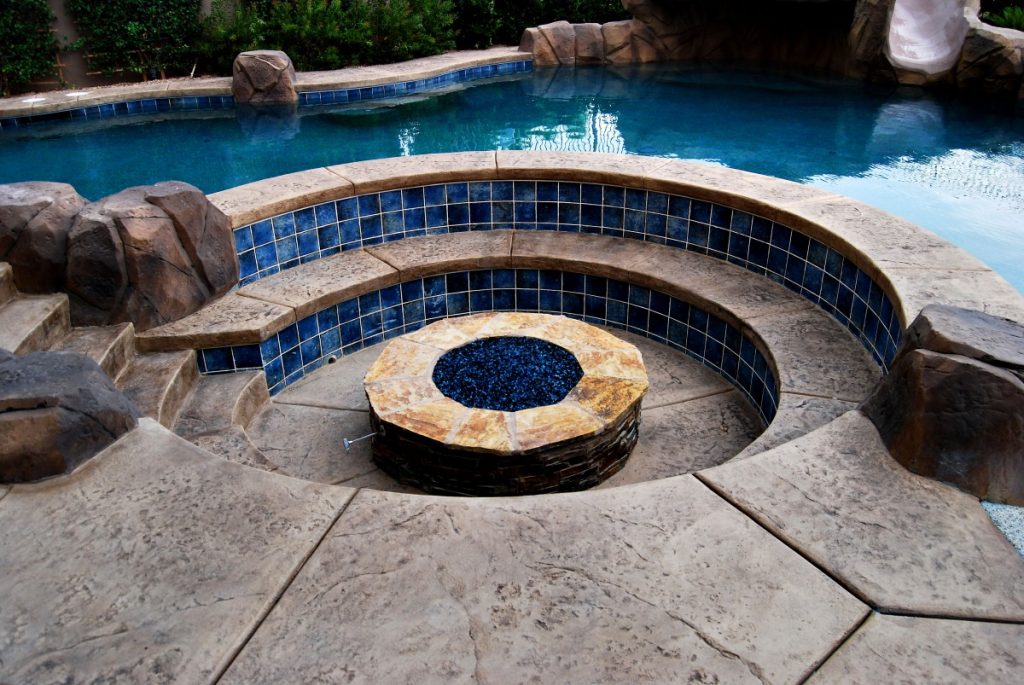Backyard pool area with a custom fire pit by Chicago Landscape