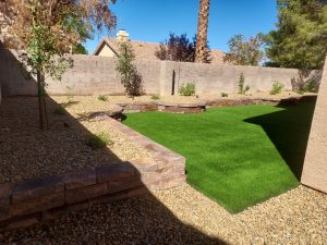 This complete backyard transformation by Chicago Landscape of Las Vegas showcases a seamless integration of functional hardscaping and water-smart greenery. The design features a large interlocking paver patio and a matching side walkway that transitions into a lush, synthetic turf lawn and elevated stone planter beds. The final result is a multi-textured outdoor oasis that combines professional masonry with low-maintenance desert landscaping and modern irrigation.