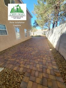 This complete backyard transformation by Chicago Landscape of Las Vegas showcases a seamless integration of functional hardscaping and water-smart greenery. The design features a large interlocking paver patio and a matching side walkway that transitions into a lush, synthetic turf lawn and elevated stone planter beds. The final result is a multi-textured outdoor oasis that combines professional masonry with low-maintenance desert landscaping and modern irrigation.