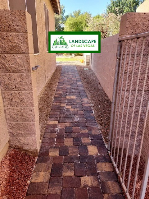 A professionally installed stone paver walkway winding through a residential front yard in Southern Highlands, Las Vegas, featuring desert-friendly landscaping and decorative rock borders.