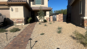 Complete front yard landscape conversion in Henderson, NV featuring premium interlocking stone pavers, decorative landscape rock, native plants, and custom lighting.