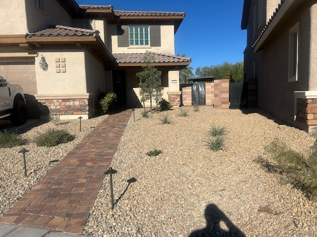 Complete front yard landscape conversion in Henderson, NV featuring premium interlocking stone pavers, decorative landscape rock, native plants, and custom lighting.