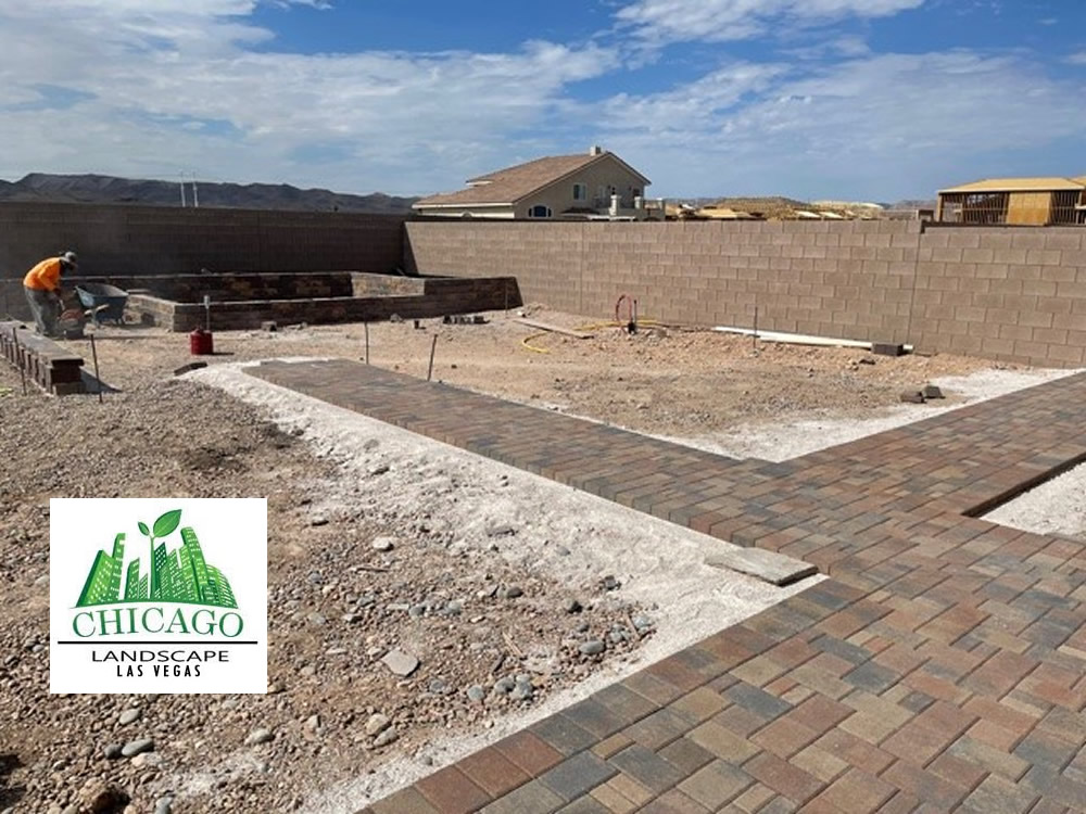 Backyard landscape renovation in progress in Las Vegas with demolition, paver installation, raised beds, irrigation work, and artificial turf preparation.