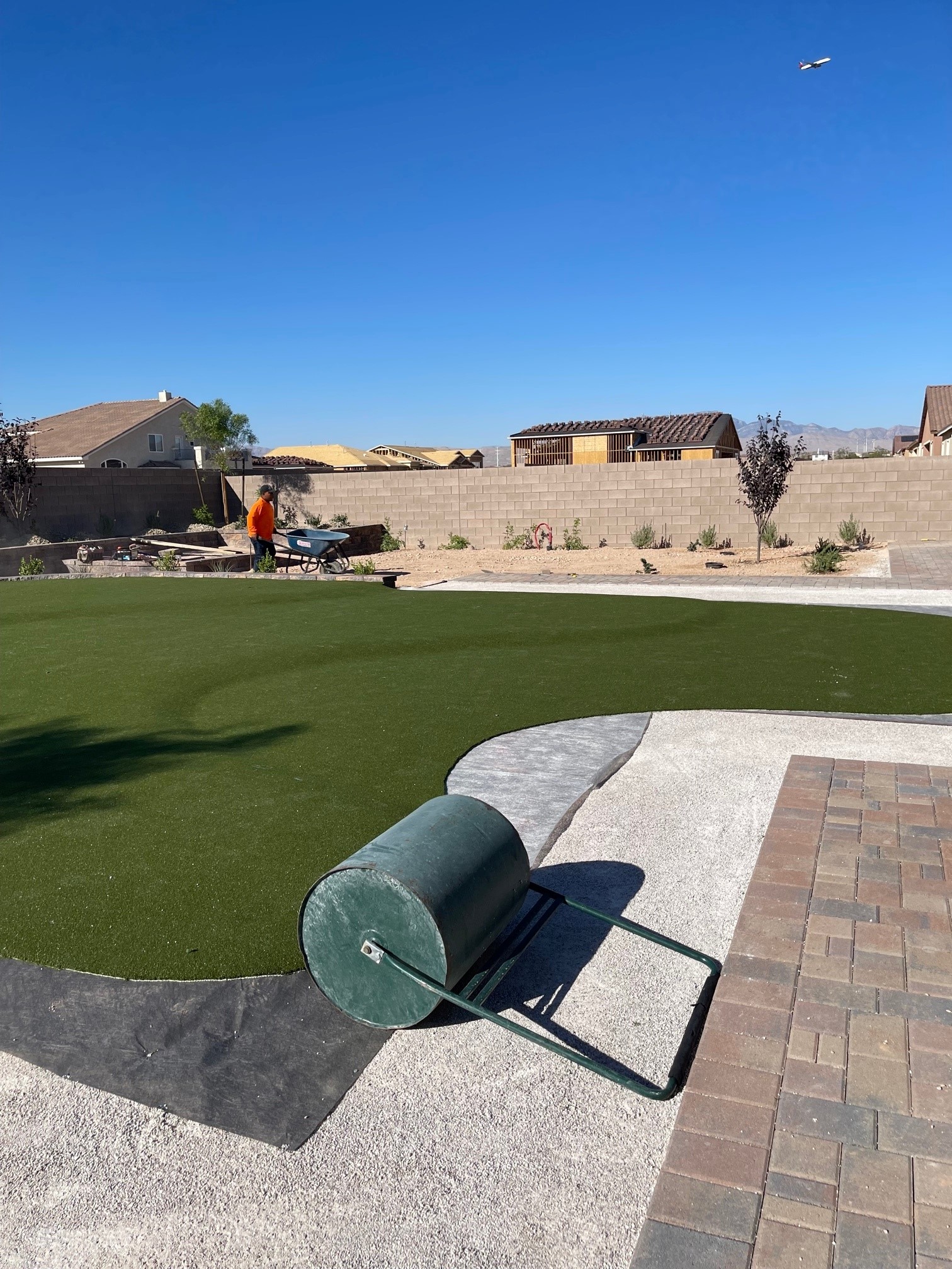 Backyard landscape renovation in progress in Las Vegas with demolition, paver installation, raised beds, irrigation work, and artificial turf preparation.