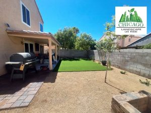 Photo shows backyard with trees, artificial turf and pavers installed