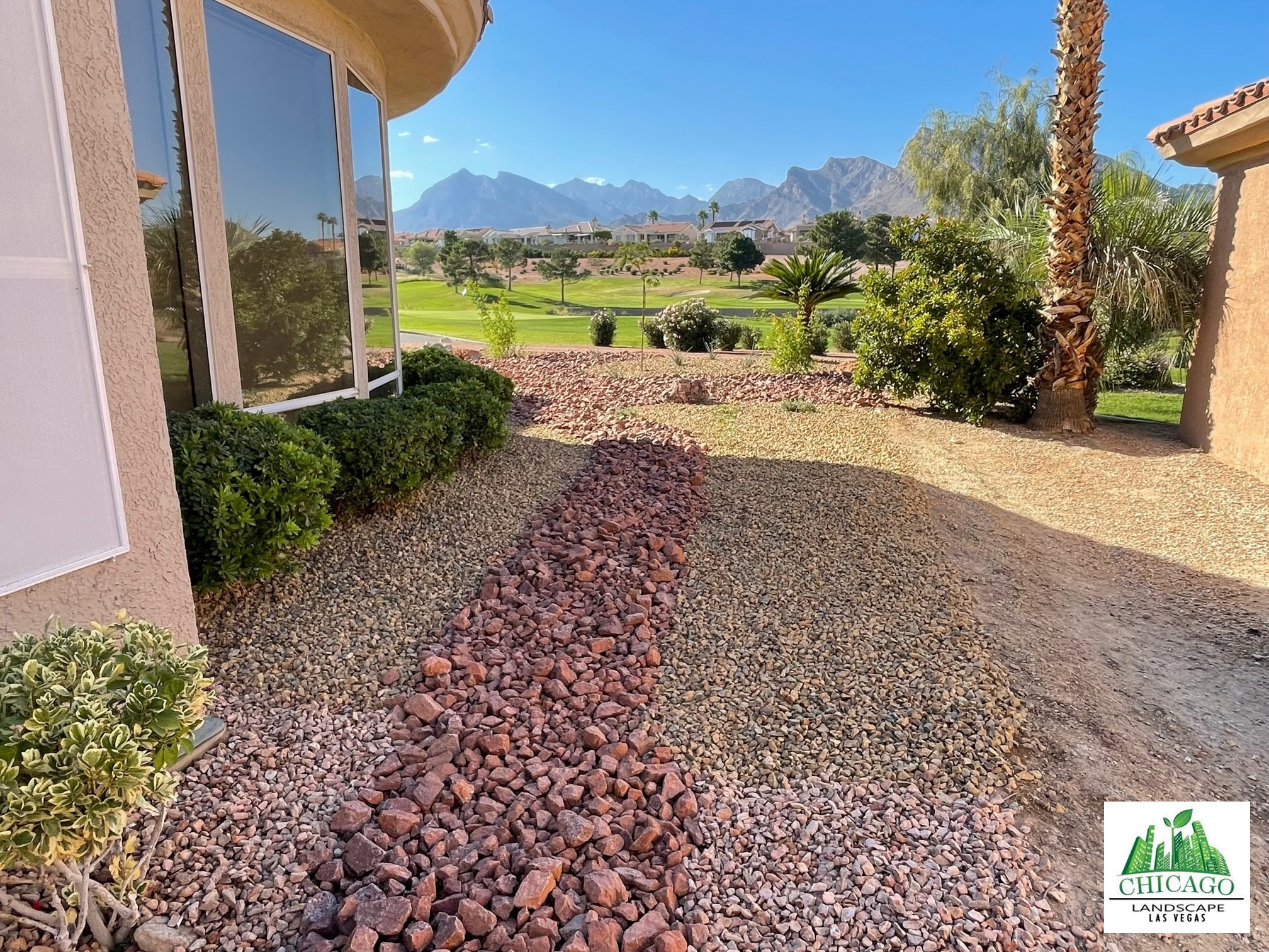 Decorative rock and planting beside the home with golf-course and mountain views.