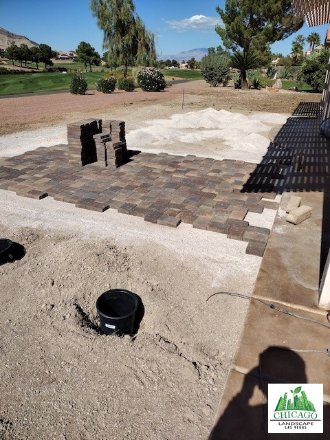 Backyard pavers being installed beside the patio with the golf course beyond.