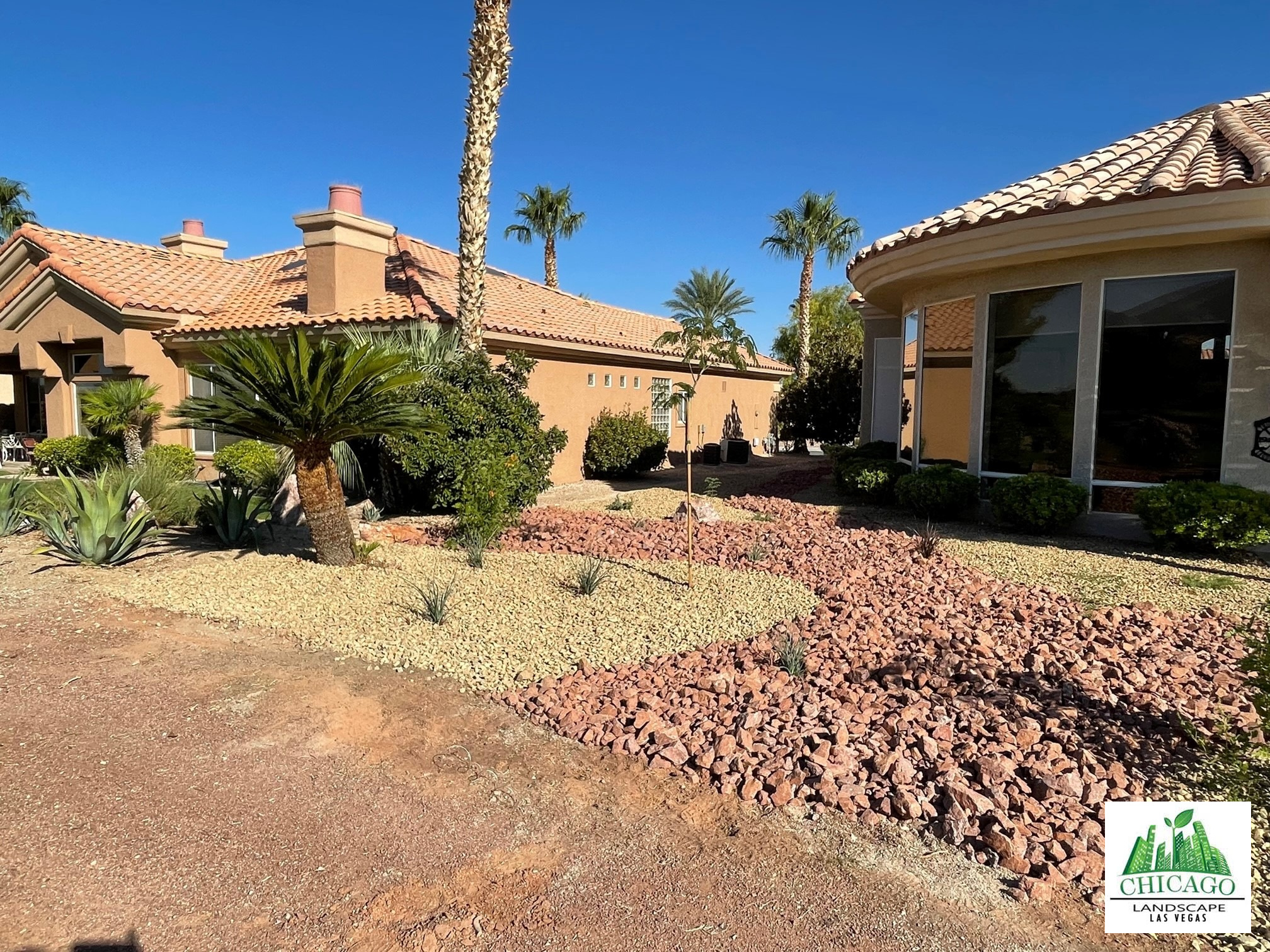 Curving bands of decorative rock with new planting beside the home.