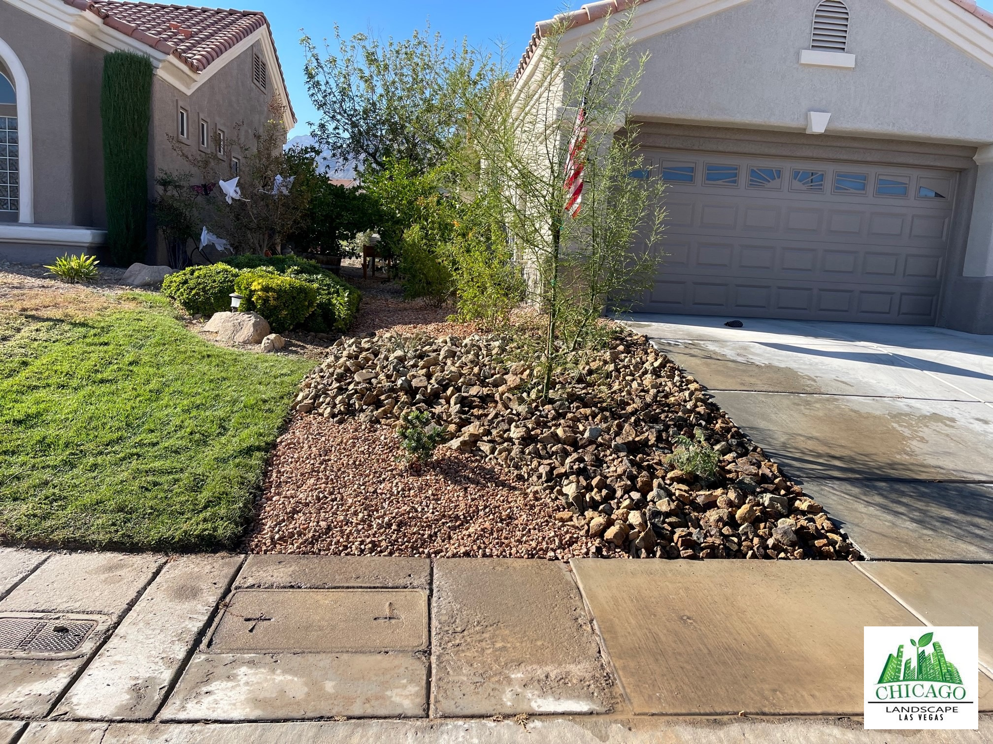 Rock planting bed with a young tree beside the driveway.