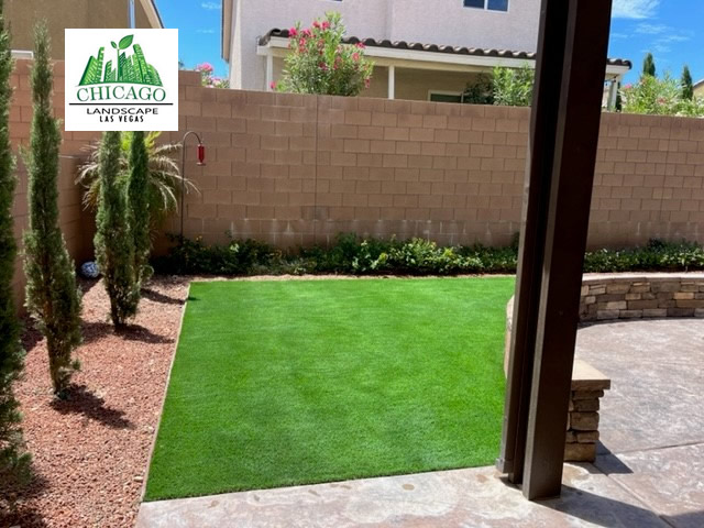 Completed artificial-turf area bordered by shrubs, Italian Cypress, landscape rock, and a curved decorative wall.